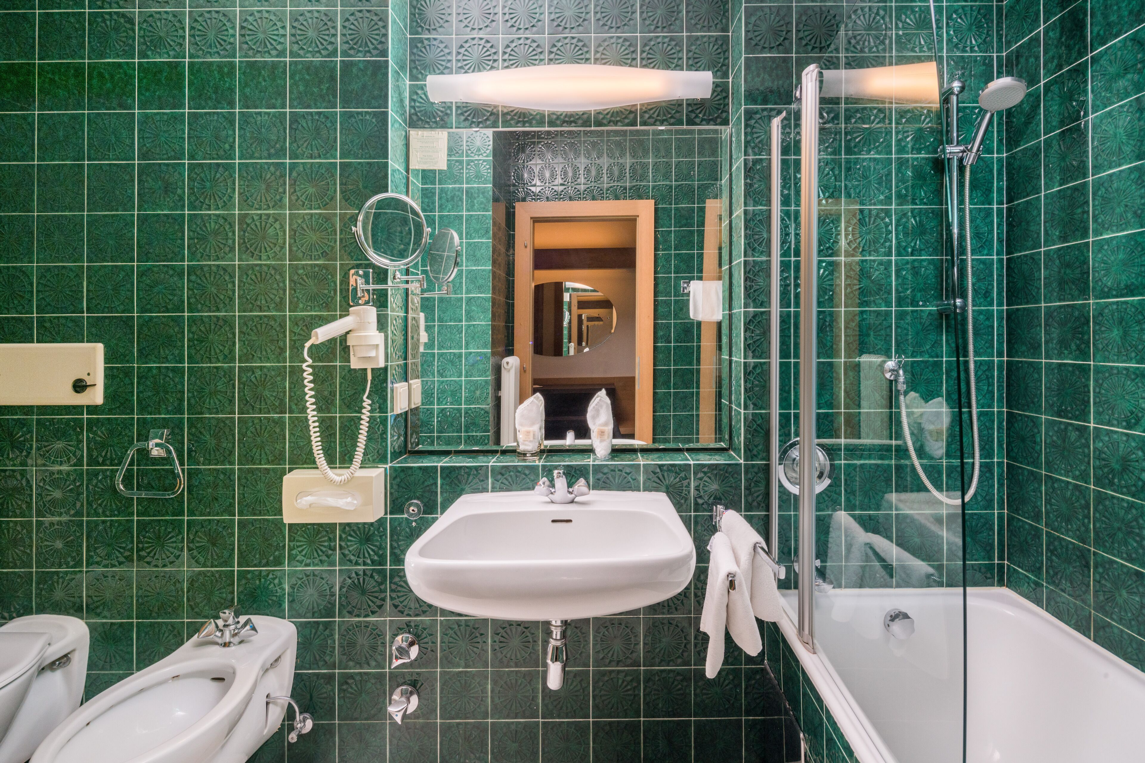 A bathroom with a sink, mirror, and shower.