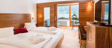 A modern hotel room with a large bed, wooden headboard, a desk, and a television.