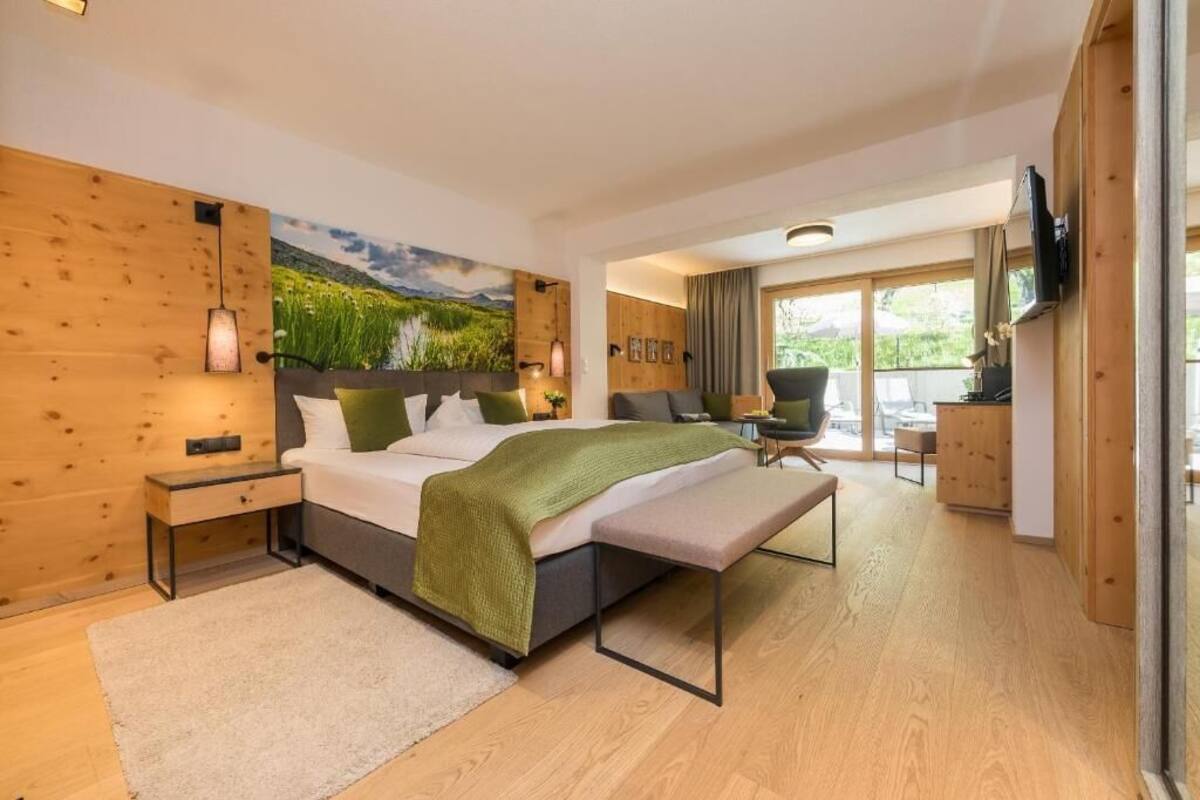 Un dormitorio moderno con una cama grande, un banco, un escritorio y un televisor.