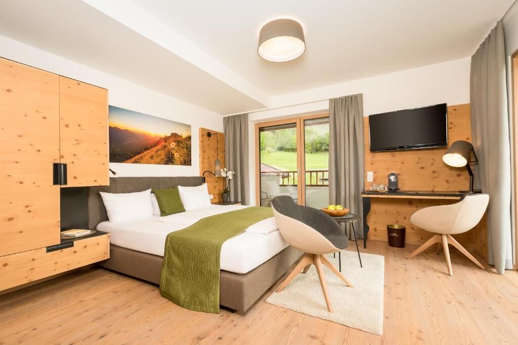Habitación de hotel moderna con cama, escritorio, televisor y vistas al exterior.