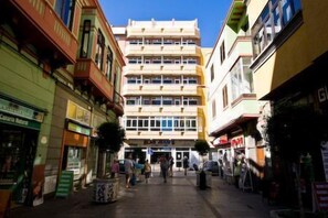 Un edificio de varios pisos con una entrada central y una acera para peatones.