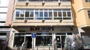 Una fachada comercial con un letrero que dice "BLAS JEANS" y un letrero azul de estacionamiento reservado para discapacitados.