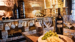Une cave à vin avec des bouteilles, des verres et un plateau de fromages.