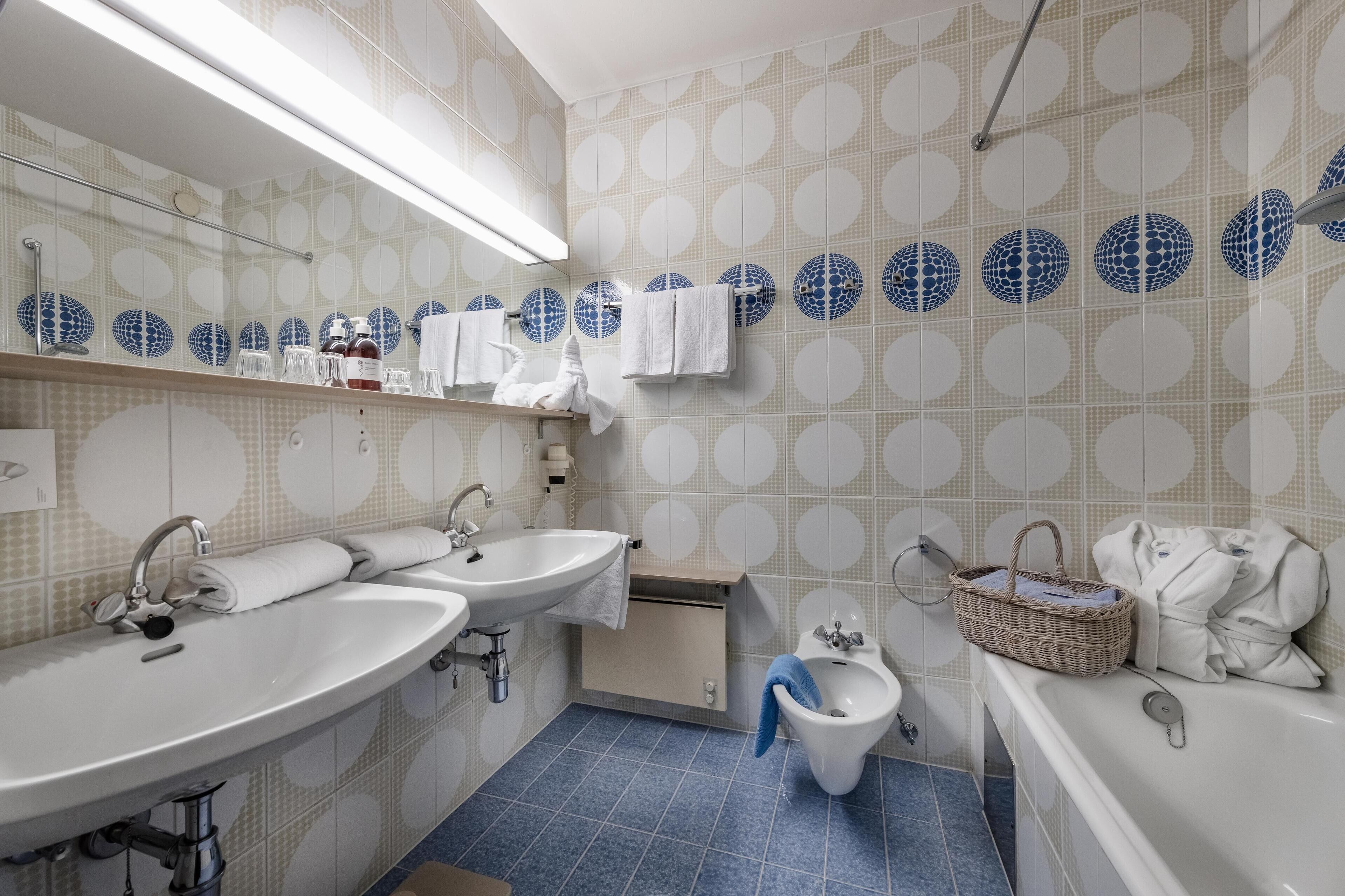Un baño con dos lavamanos, un bidé y una bañera. Hay toallas y artículos de aseo en el mostrador.