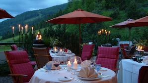 Un espace de restauration en plein air, avec des tables dressées pour le repas, entouré de parasols rouges et agrémenté de bougies sur chaque table.