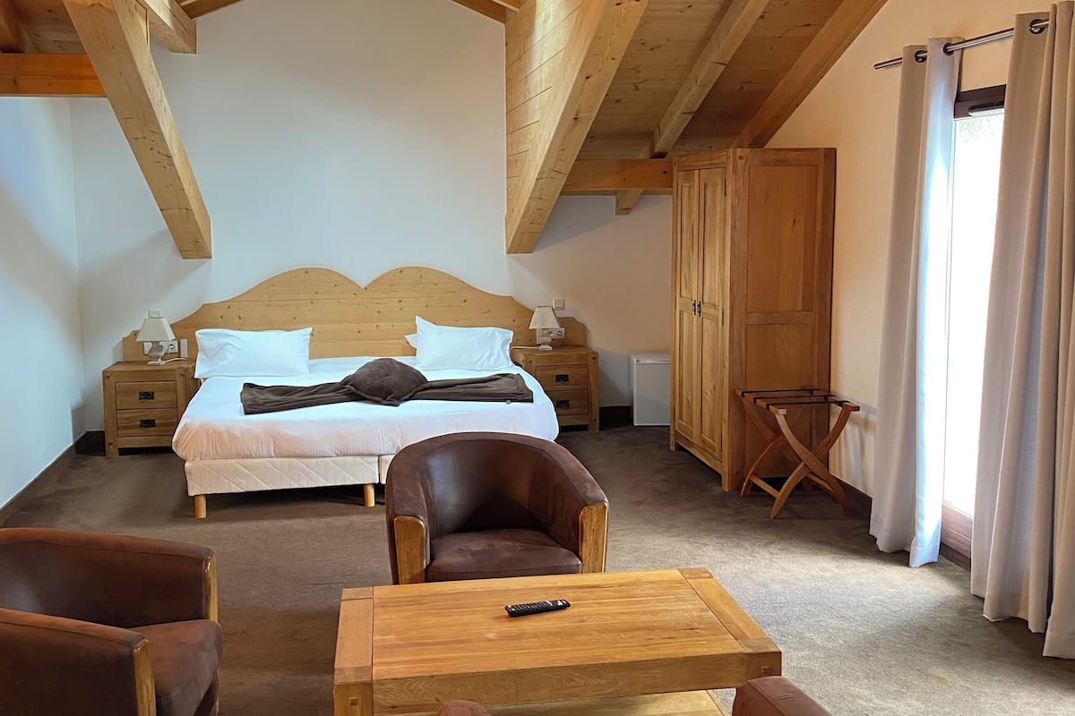 Une chambre avec un plafond en bois, un lit, un bureau et deux chaises.