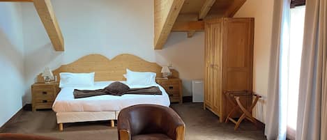 Un dormitorio con techo de madera, una cama, un escritorio y dos sillas.