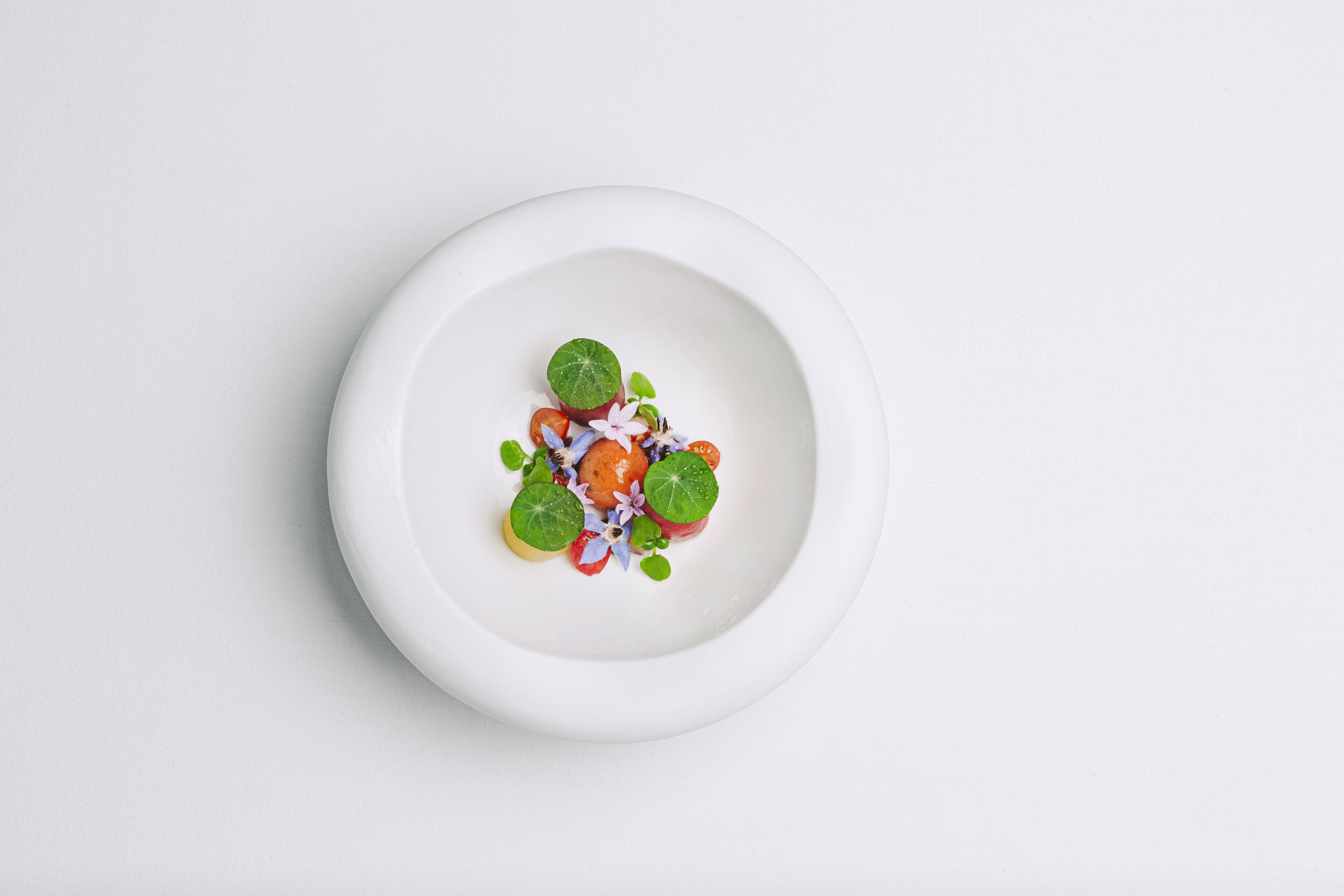 A white plate with a salad on a white background.