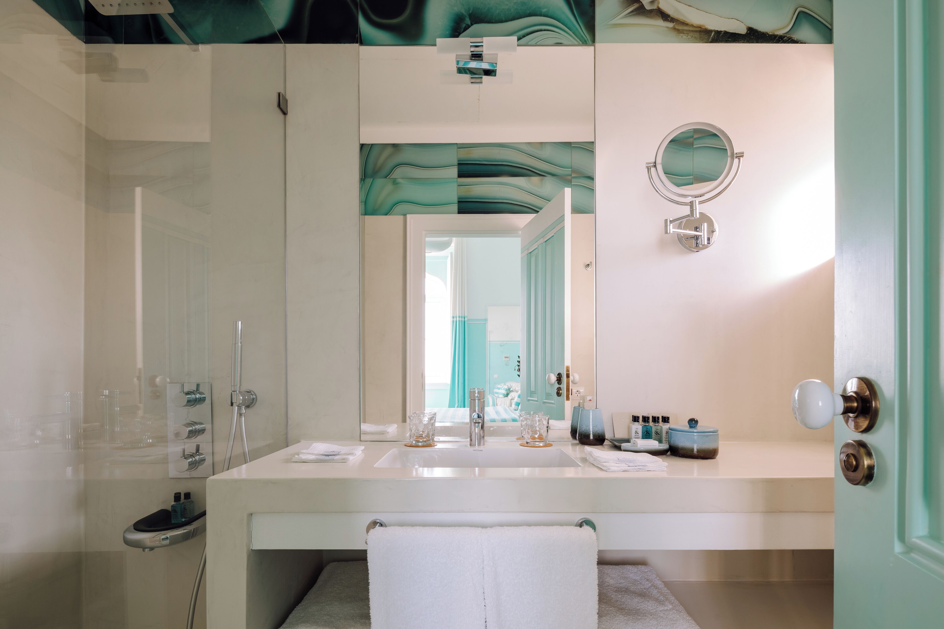 Un baño con un lavabo blanco, un espejo, un toallero y una zona de ducha.