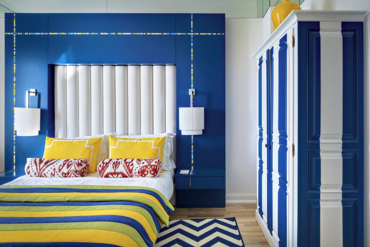A bedroom with a large bed, a nightstand, a lamp, and a wardrobe.