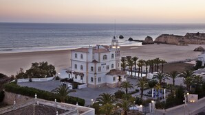 A coastal building with a prominent tower, adjacent to a beach and palm trees.