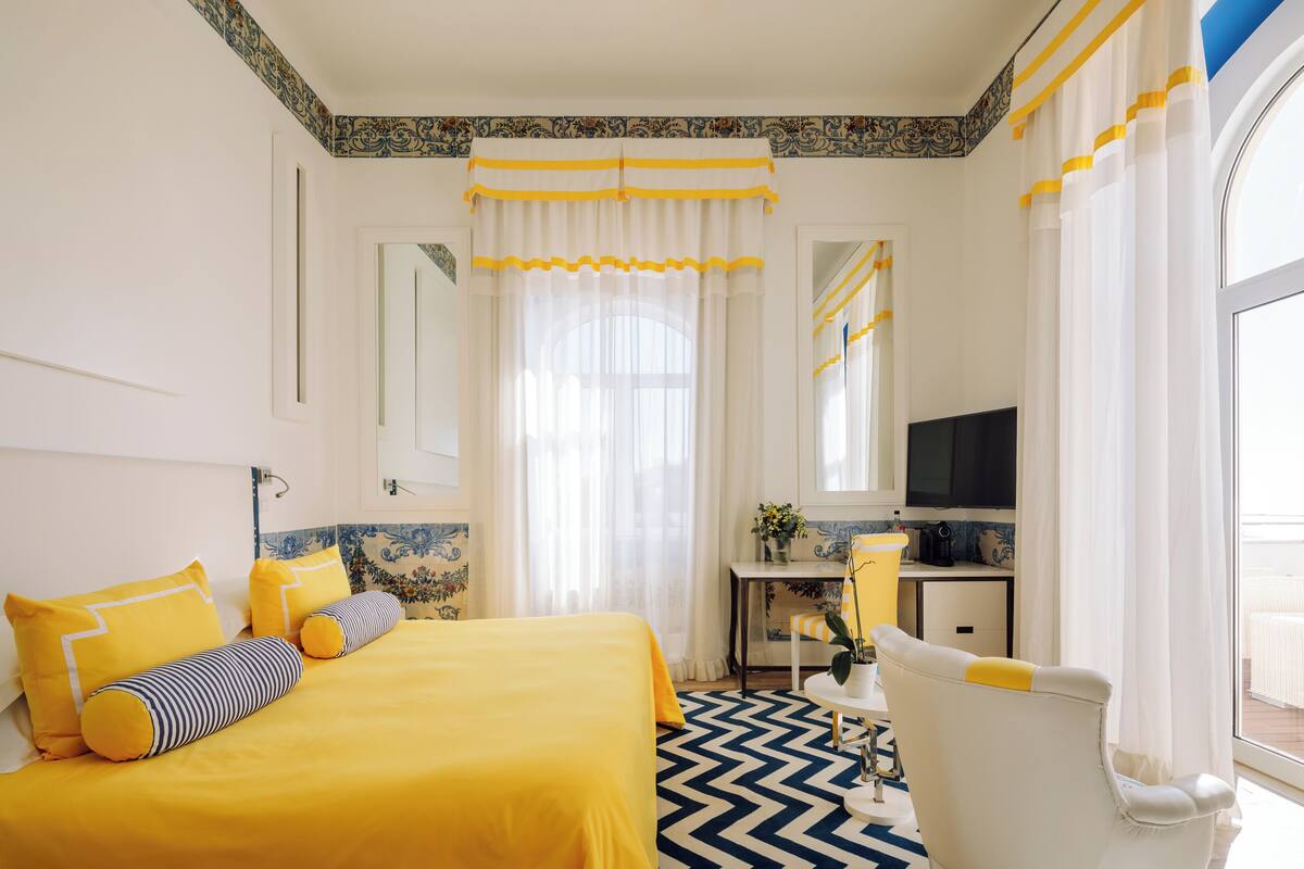 A hotel room with a bed, a desk, a chair, and a TV.