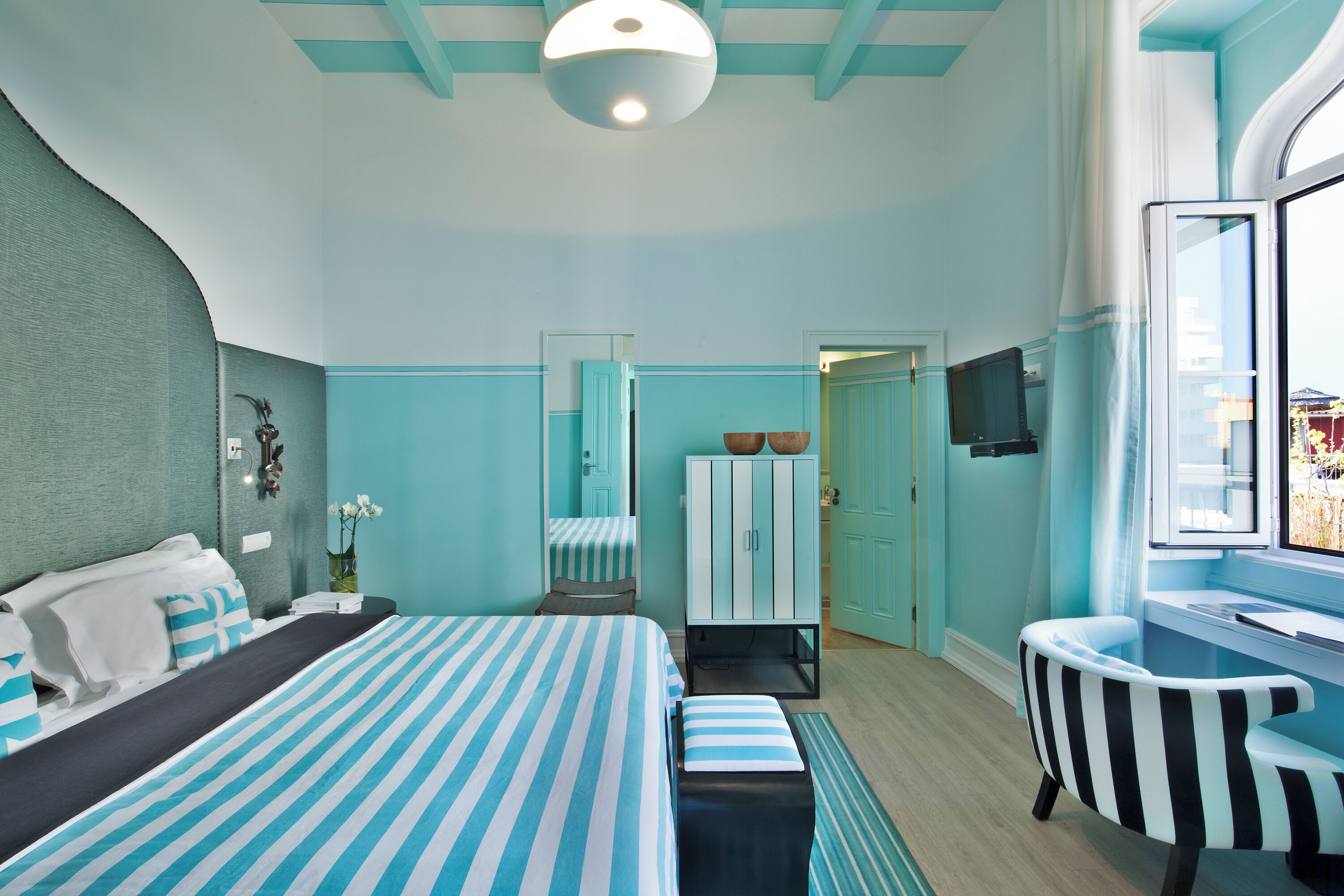 Une chambre d’hôtel équipée d’un lit, d’un bureau, d’une chaise, d’une télévision et d’une fenêtre donnant sur un paysage agréable.