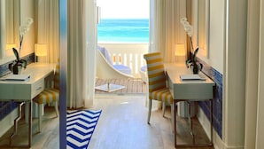 A room with a view of the ocean, featuring two chairs, a desk, and a blue and white rug.