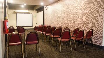 A conference room with rows of red chairs, a whiteboard, and a fire extinguisher.