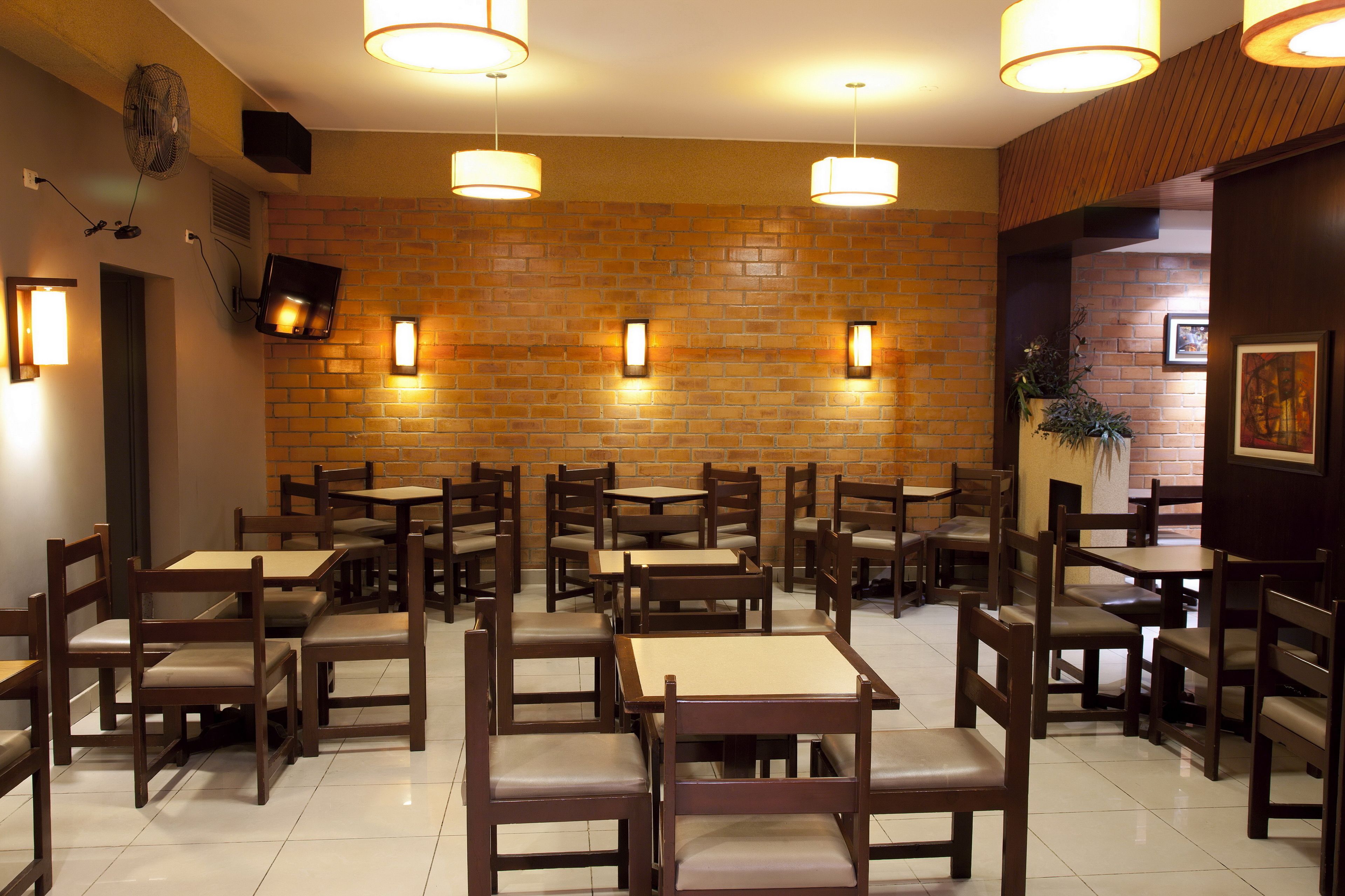 Un restaurante con paredes de ladrillo, mesas y sillas de madera, e iluminación colgante.