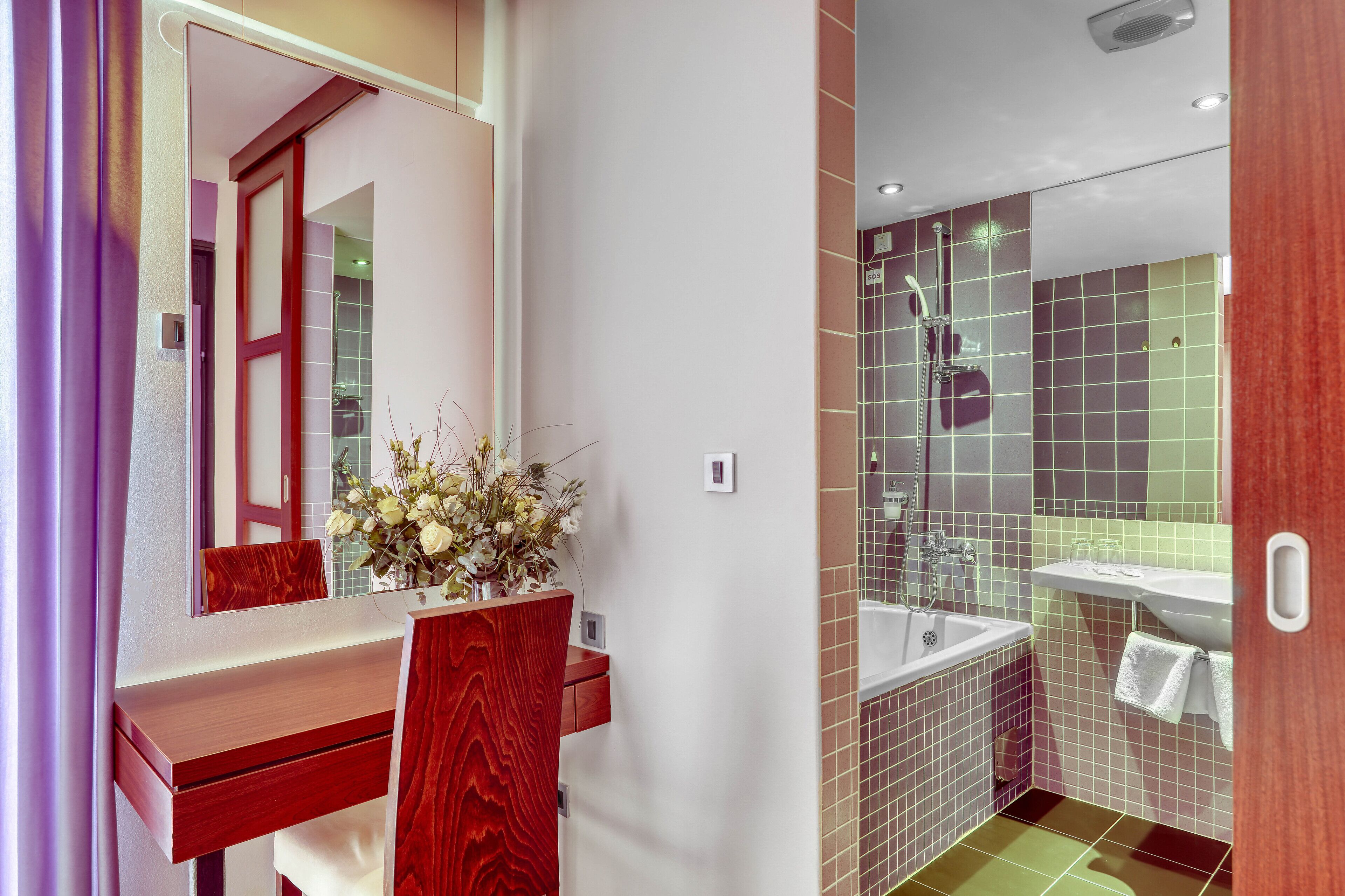 A modern bathroom with a wooden vanity, a mirror, and a shower area.