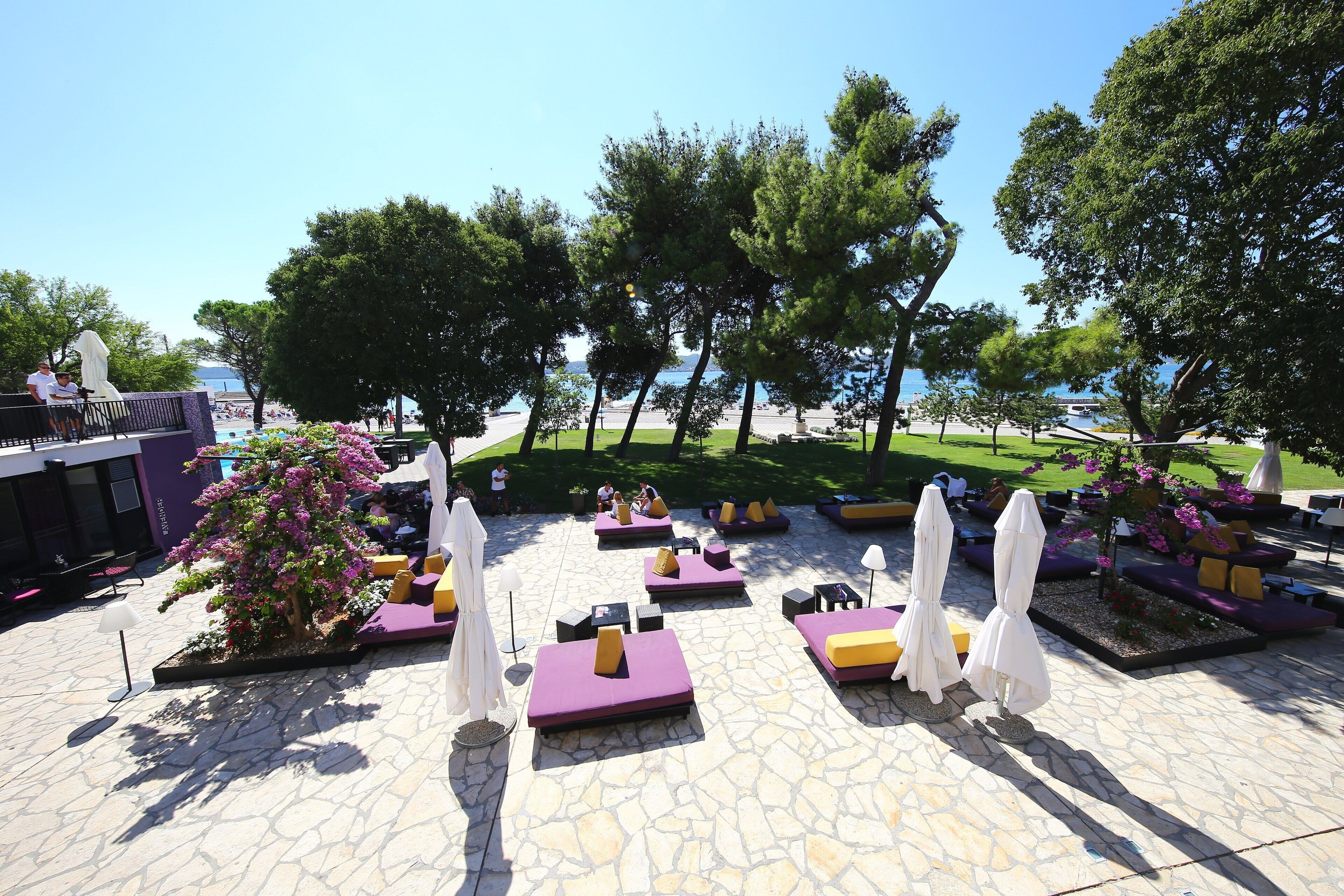 An outdoor seating area with stone flooring, cushioned seating, and umbrellas.