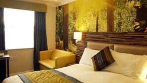 A hotel room with a bed, a chair, a nightstand, and a large forest-themed wall mural. - B&B Hotel Manchester SportCity (Manchester)