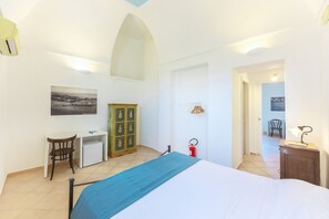 A bedroom with a bed, a desk, a chair, a wardrobe, and a fire extinguisher. - Palazzo Attila - Gioia Apartments (Procida)