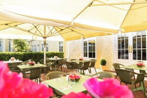 An outdoor patio with round tables and chairs, covered by large umbrellas, and a hedge in the background. - Seven Oaks Hotel with Heated Indoor Pool and Fitness Centre Carlow Town (Carlow)