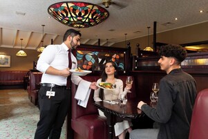 A restaurant with a waiter serving food to a table.