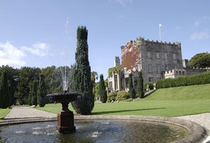 A historic building with a fountain and well-manicured lawn.