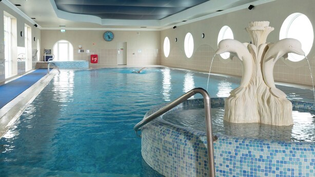 An indoor swimming pool with a tiled edge, a handrail, and a decorative fountain. - Seven Oaks Hotel with Heated Indoor Pool and Fitness Centre Carlow Town (Carlow)