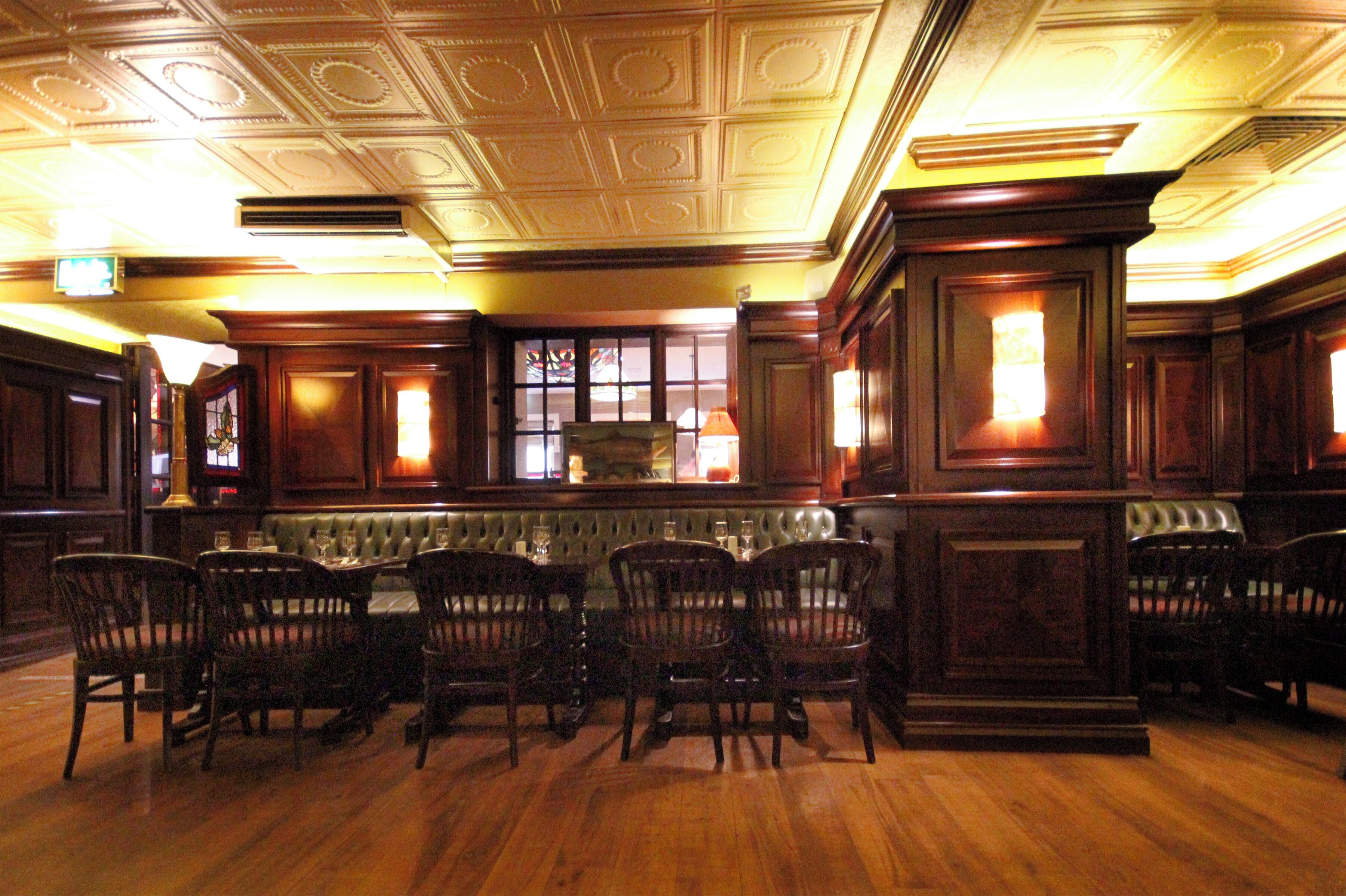 Un comedor formal con techo alto, paneles de madera ornamentados y una disposición central de asientos.