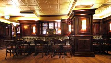 Un comedor formal con techo alto, paneles de madera ornamentados y una disposición central de asientos.