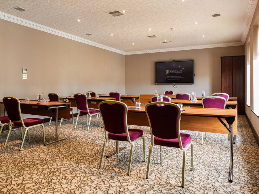 Un salón de conferencias con una pantalla grande, varias mesas y sillas.