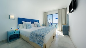 A hotel room with a large bed, a nightstand, a dresser, and a balcony with a view of the sea. - Apartamentos Igramar MorroJable - Adults Only (Pajara)