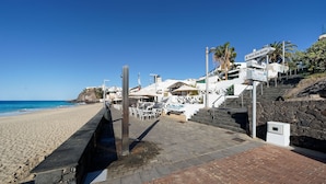 A coastal hotel with outdoor seating, a stone staircase, and a view of the beach and ocean. - Apartamentos Igramar MorroJable - Adults Only (Pajara)