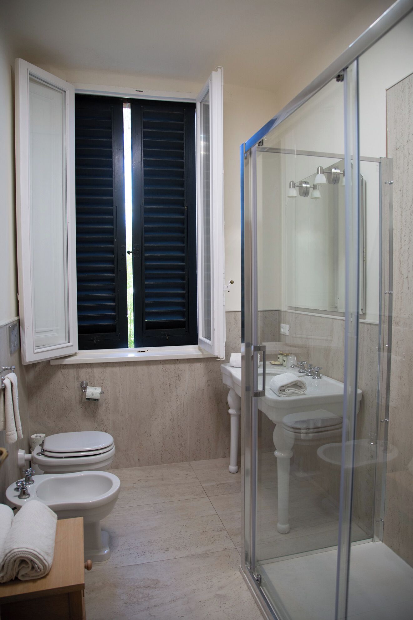 Un bagno con servizi igienici, bidet, lavandino e doccia con pareti in vetro.