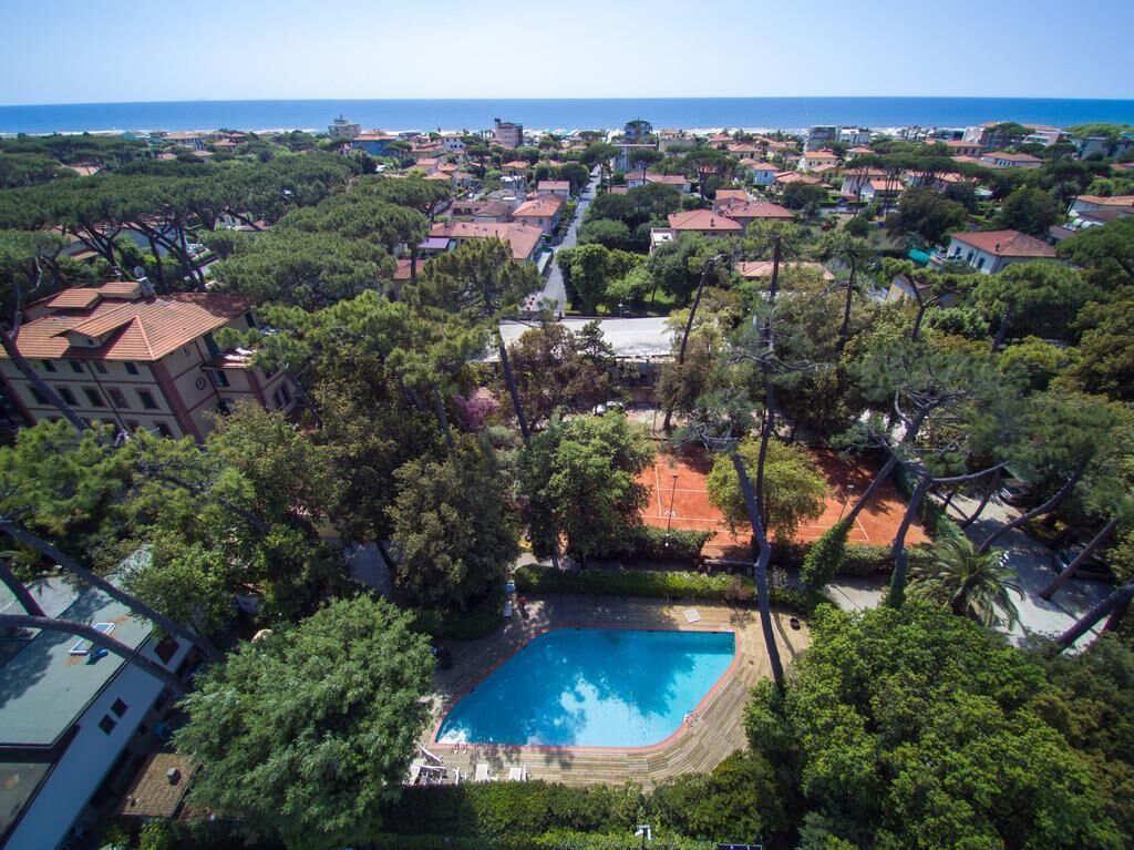 An aerial view of a residential area with a swimming pool surrounded by trees and buildings.