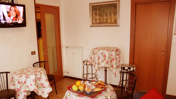 Comedor con dos mesas, sillas, una cesta de frutas y un televisor.