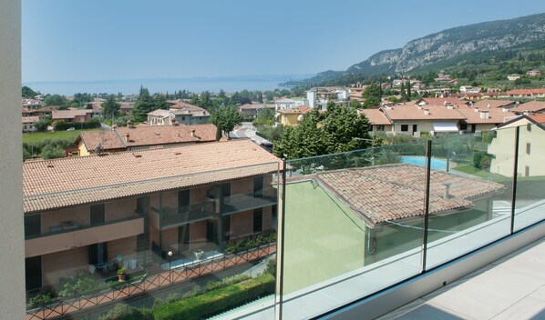 Un quartier résidentiel aux toits recouverts de tuiles en terre cuite, offrant une vue dégagée sur la mer et s’étendant devant un paysage montagneux.