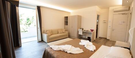 A hotel room with a bed, a sofa, a desk, and a wardrobe.