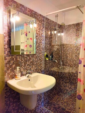 Une salle de bain avec une douche, un lavabo et un miroir.