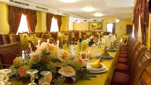 A formal dining room with multiple tables set for service, featuring floral centerpieces and formal table settings. - La Madonnina (Budduso)