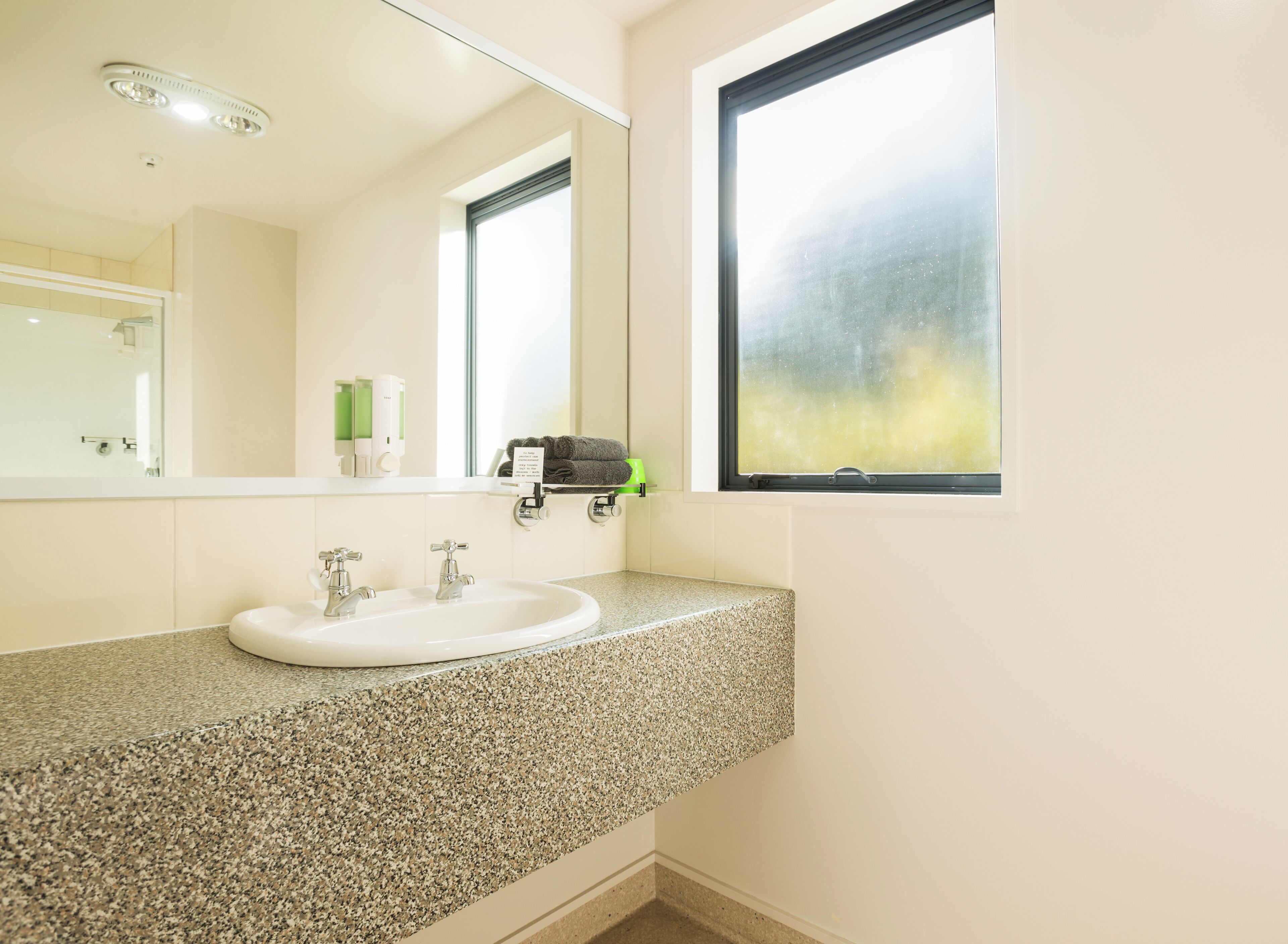 A bathroom with a granite countertop, white sink, and a large mirror.