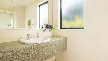 A bathroom with a granite countertop, white sink, and a large mirror.