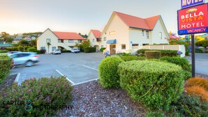 A motel with a red roof, a signboard, and a parking lot with cars. - Bella Vista Motel Oamaru (Oamaru)