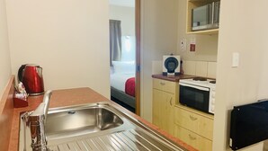 A compact kitchen with a stainless steel sink, a microwave, and a stove. - Bella Vista Motel Oamaru (Oamaru)