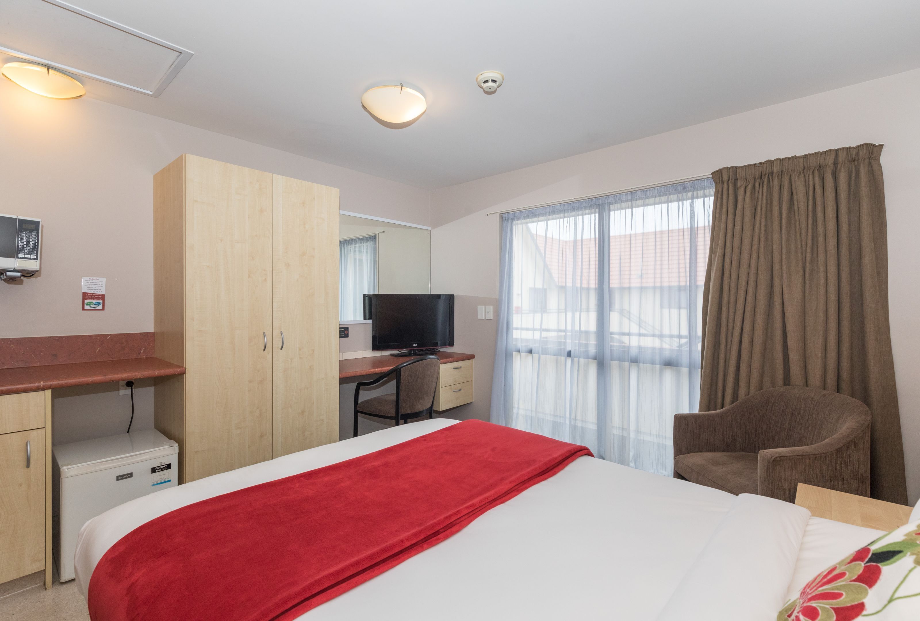 A hotel room with a bed, a desk, a television, and a chair.