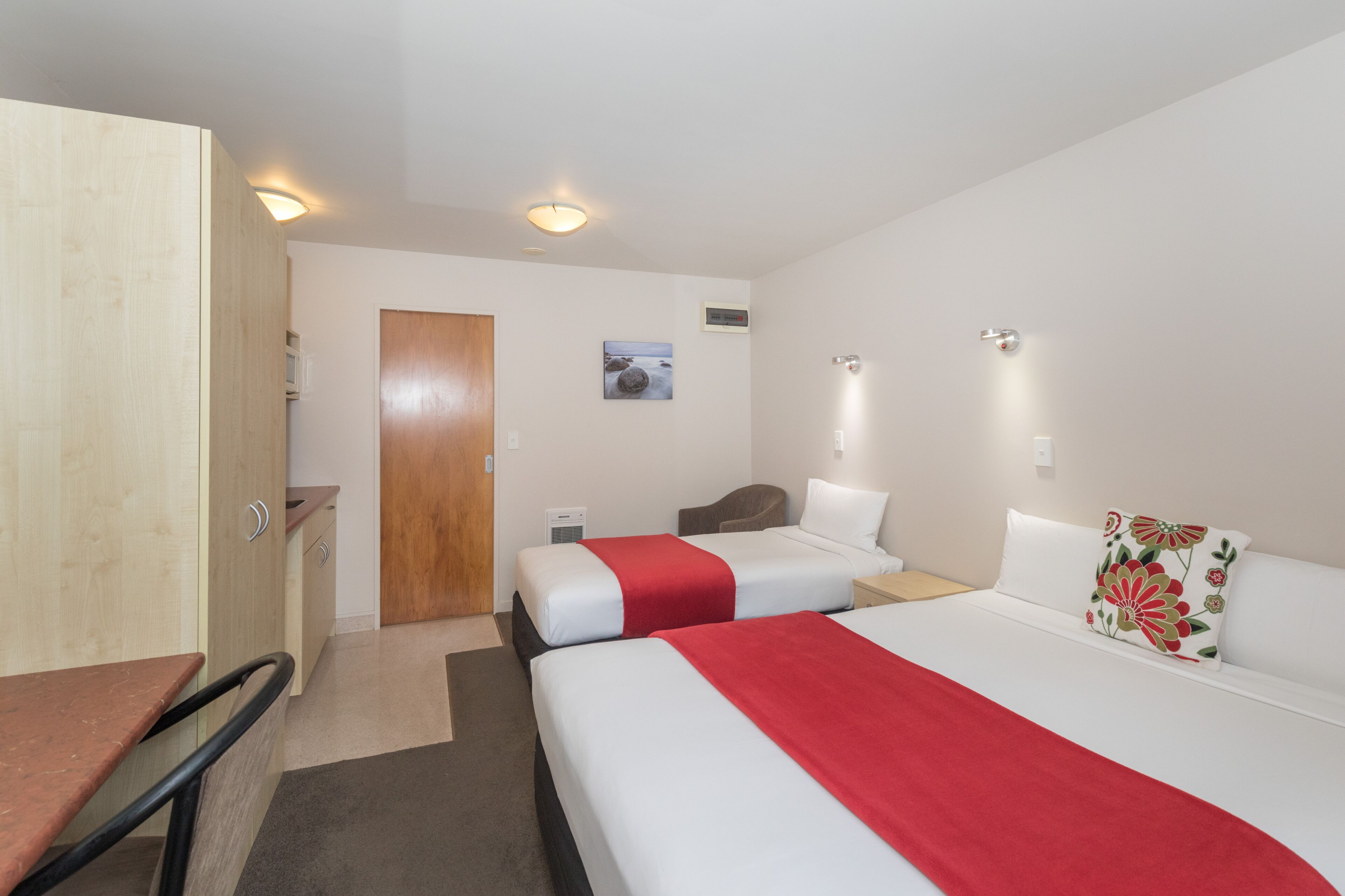 Ein Hotelzimmer mit zwei Betten, einem Schreibtisch und einem Kleiderschrank.