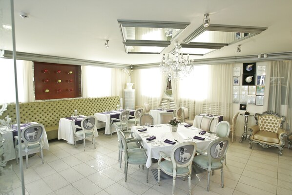 A dining area with multiple tables, chairs, and a chandelier.