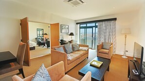 A hotel room with a living area featuring a sofa, armchairs, a coffee table, and a TV. - La Fregate Hotel (St. Peter Port)