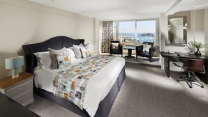 A hotel room with a large bed, a desk, a chair, and a view of the sea. - La Fregate Hotel (St. Peter Port)