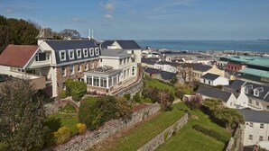 A coastal town with a prominent white building featuring a large bay window and a conservatory. - La Fregate Hotel (St. Peter Port)